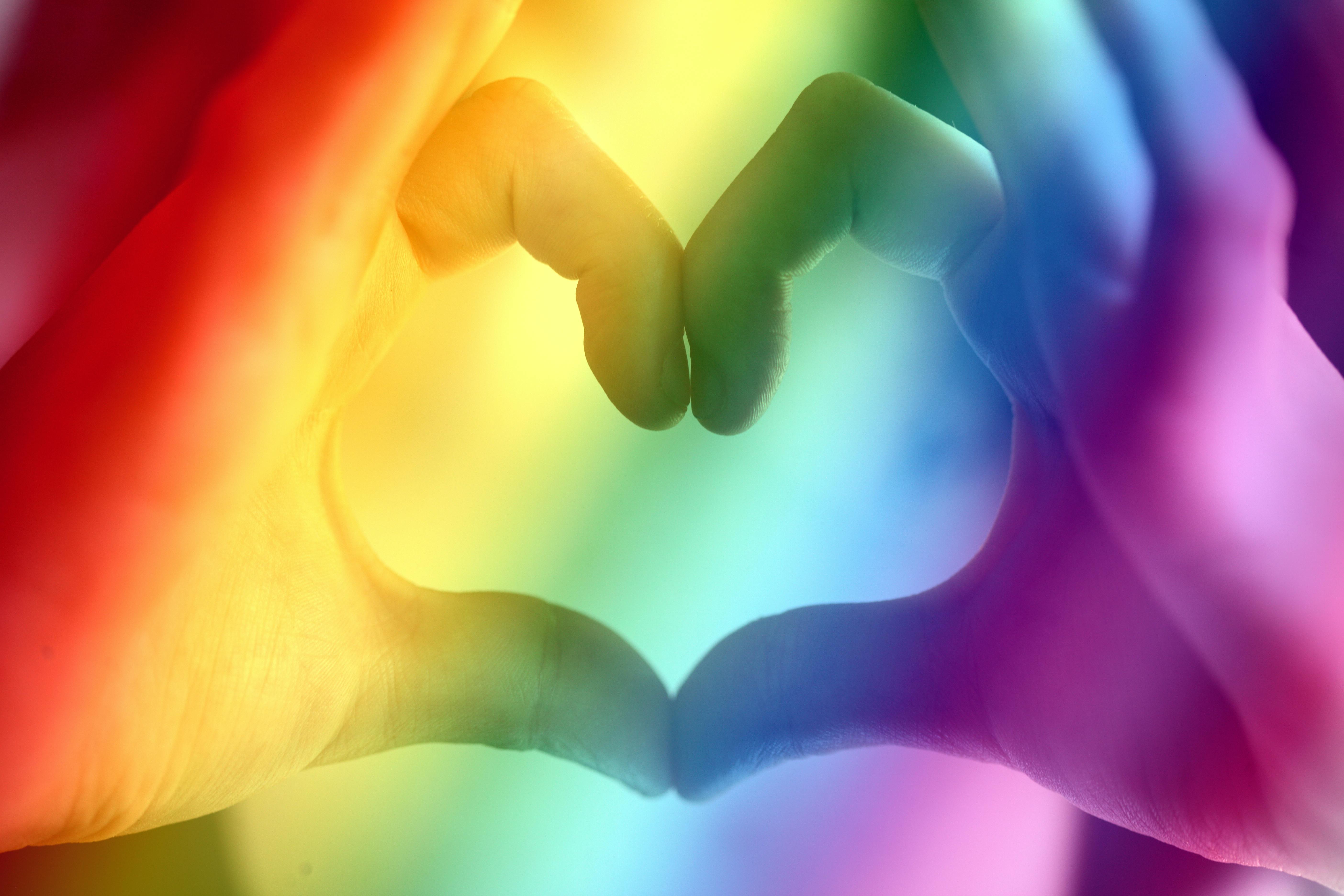 rainbow over hands shaped into a heart