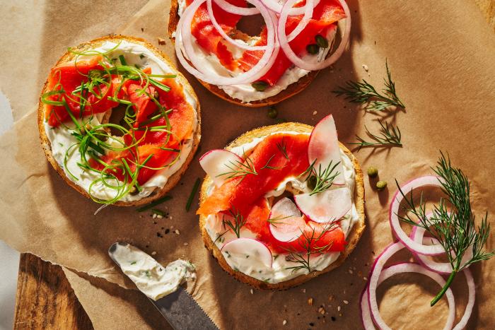 Close up of bagels with lox, onions, chives, radishes on them - photo by Kate Blakeman
