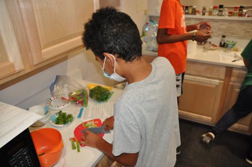 Student prepping food in ACC Summer Youth Camp course.