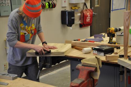 Student sanding a chair in ACC's HIVE MakerSpace during a Summer Youth Camp course.