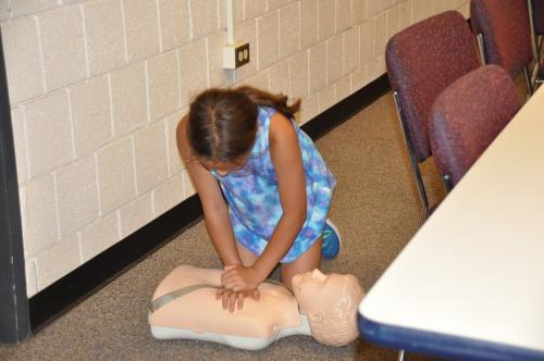 Student practicing CPR on mannequin during ACC Summer Youth Camp Course on Babysitter Training.