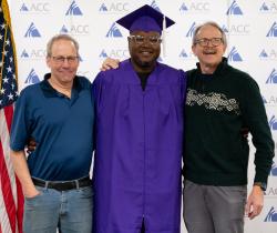 Ayanda Dladla-Ndlovu, ACC Alum, in purple regalia, with Multimedia, Graphic Design faculty members John Hall and Tom DeMoulin
