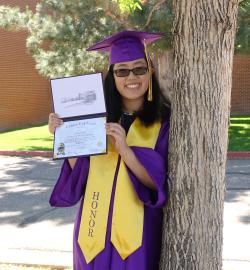 Haley Timothy wearing regalia and showing her diploma.