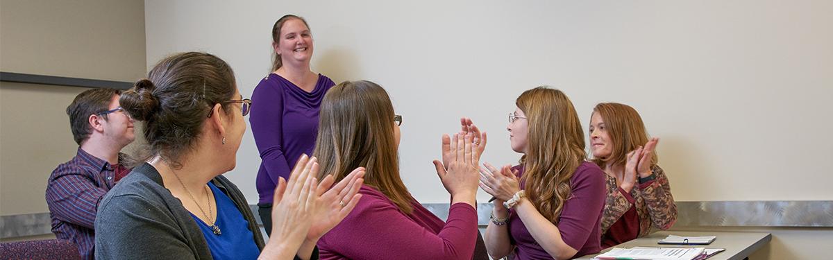 ACC students applauding a classmate in a classroom at the Littleton Campus.