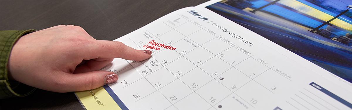 Person pointing to registration date on a calendar
