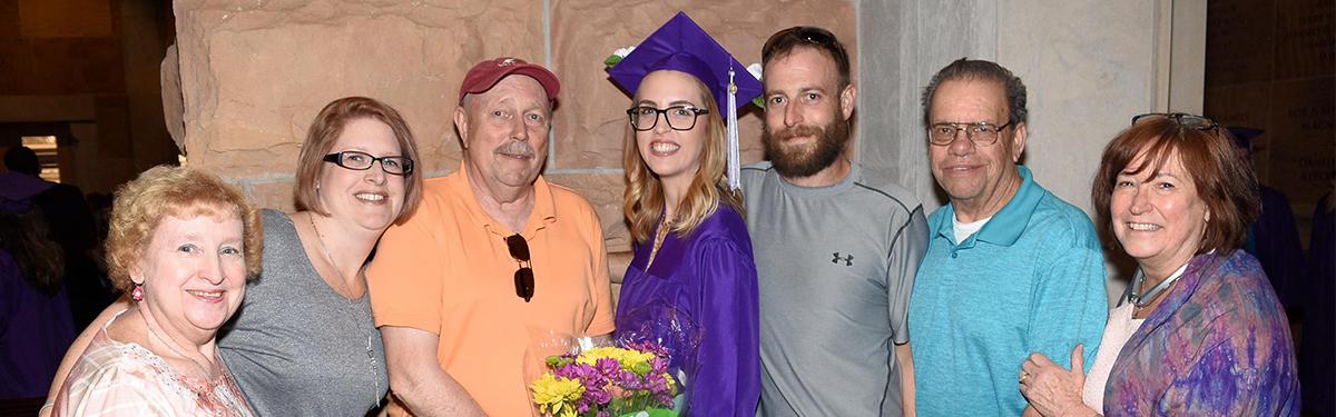 ACC Graduate posing with their family at graduation.