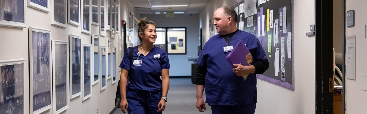 ACC Nursing students walking down the hall at the Littleton Campus, surrounded by photos of former nursing graduates.