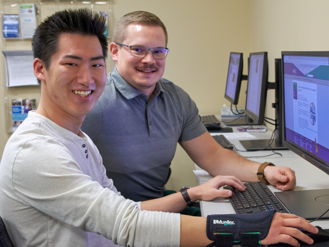 ACC Financial Aid Advisor Richard Linsacum helping student at computer with scholarship applicatio.