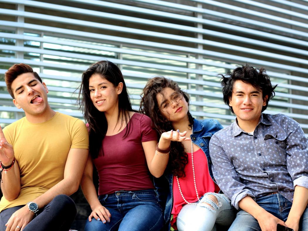 4 teenagers sitting together in front of a window.