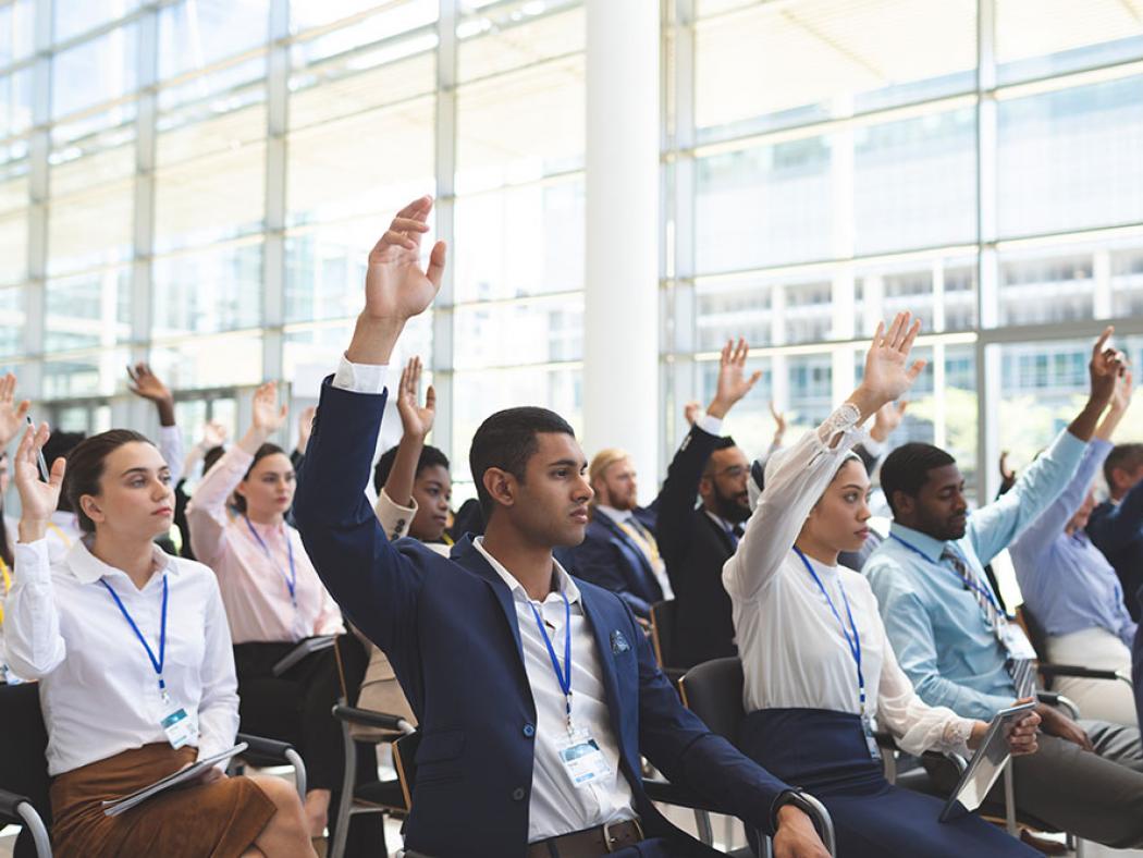 Event with people sitting and raising their hands in participation.