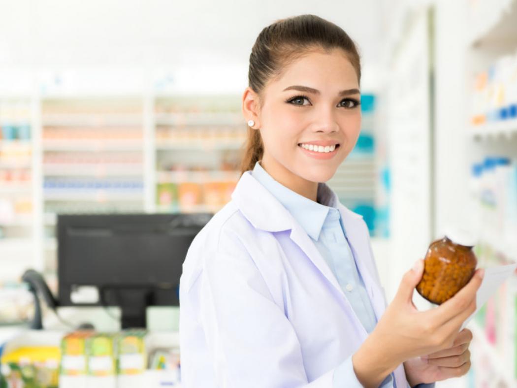 Pharmacy Technician in pharmacy with bottle of medication.