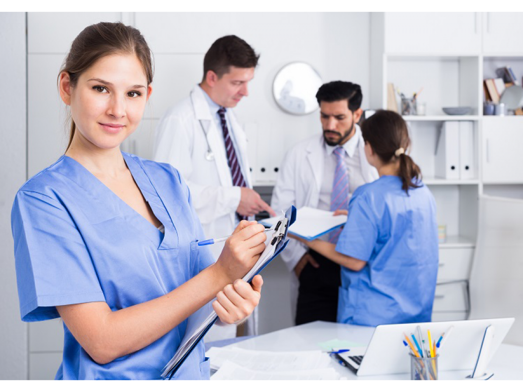 Medical student in foreground, medical staff conferring in the background.