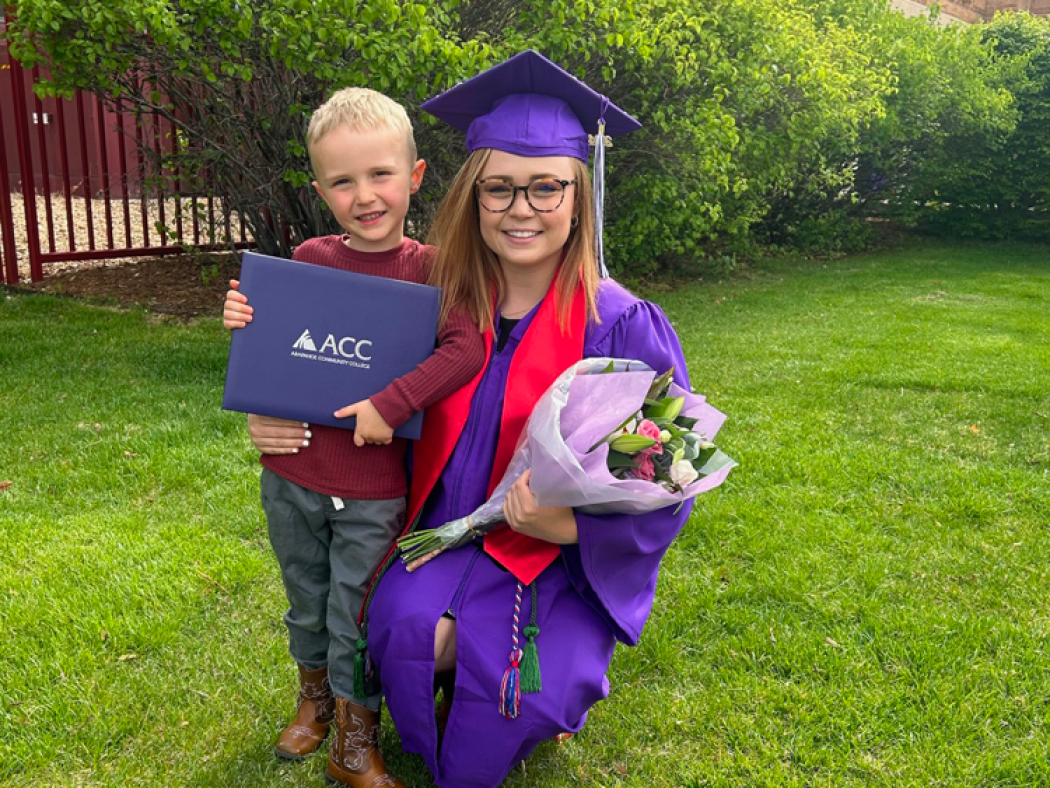 ACC Career Forward Graduate Weslyn Elder in regalia with diploma and child