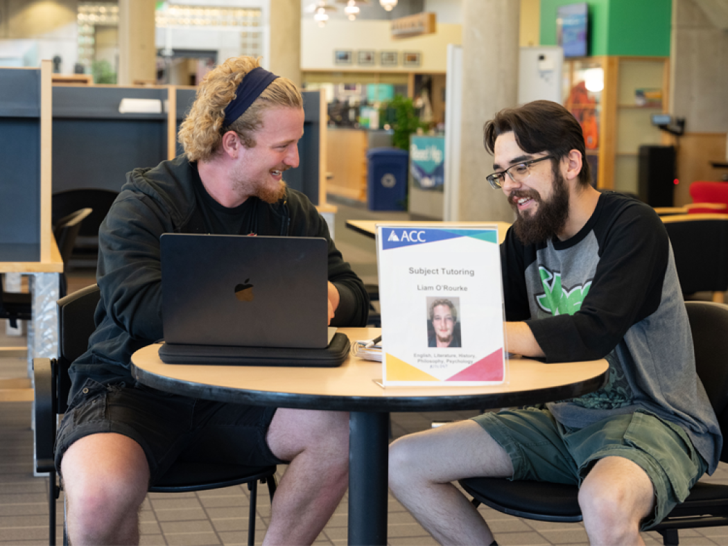 ACC tutor helping another ACC student in the Library and Learning Commons at the Littleton Campus.