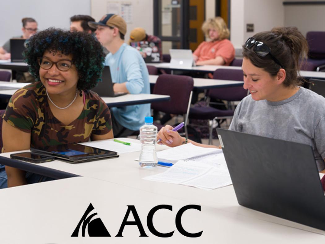 ACC students sitting at tables with laptops and ACC logo.