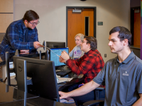 ACC student getting assistance at the Welcome Center as employees work on computers - Littleton Campus.