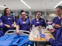 Four ACC Nursing students practicing skills around a hospital bed in a classroom at the Littleton Campus in the Health Innovation Center