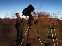 ACC student next to telescope in a field.