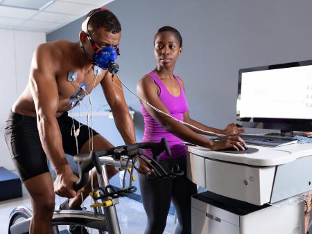 Man on a treadmill with monitors on while woman reviews input on a computer.