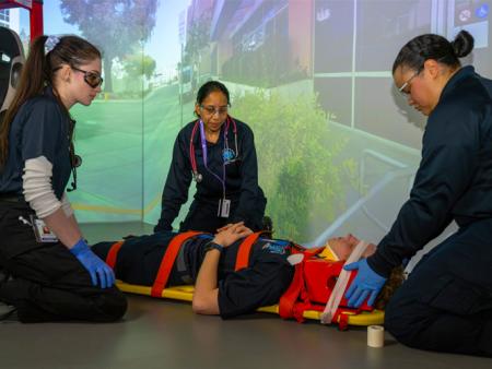 ACC EMS students in a simulation exercise placing classmate on stretcher.