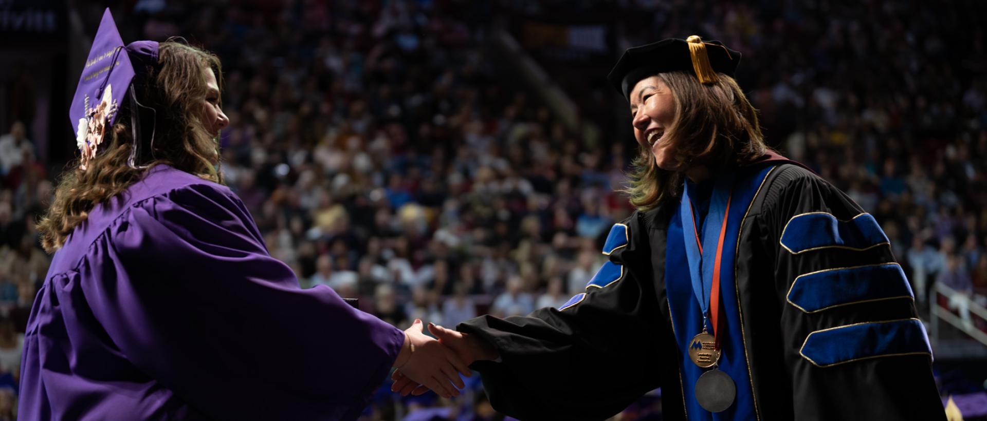 ACC graduate shaking hands with President Stephanie J. Fujii, PhD, at Commencement 