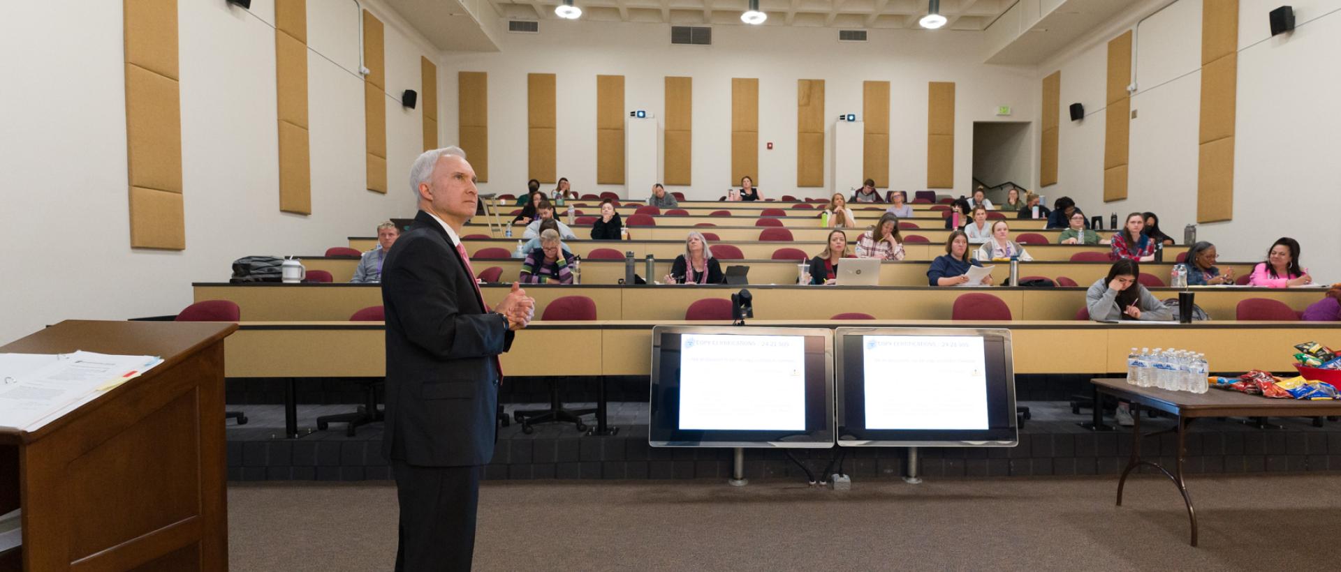 ACC Paralegal program chair standing at the front of a large classroom full of students at the Littleton Campus.