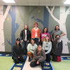 ACC Studio Art Capstone Class in front of a mural of trees and animals in ACC's Child Development Center: Tristan Dunning, Sophia Flores, Carissa Geraud, Nathan Klein, Eun Mi Lam, Lena LeBlanc, Max McMann, Jordan Stuart, and Tami Tamayo