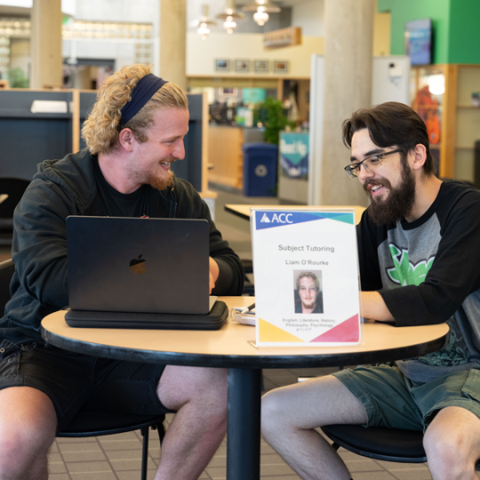 ACC tutor helping another ACC student in the Library and Learning Commons at the Littleton Campus.